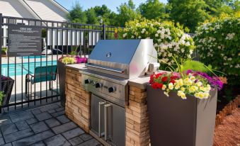 a backyard with a grill , flower pots , and a pool , all decorated with flowers and greenery at Residence Inn Boston Andover