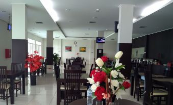 a restaurant with tables and chairs , a vase of flowers in the foreground , and a television on the wall at Hotel Bonero Residence