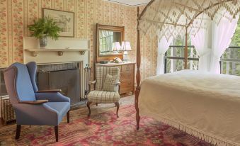 a cozy bedroom with a large bed , a chair , and a fireplace , all decorated in warm colors at Harbourside Inn