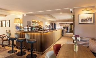 a bar area with several chairs and tables , as well as a dining table in the background at The Barnsdale, Rutland