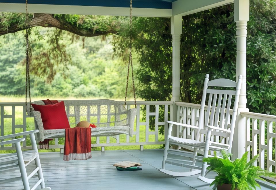 a porch with white rocking chairs and a wooden porch swing , surrounded by lush greenery at BlissWood B&B Ranch