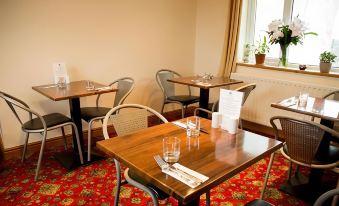 a dining room with wooden tables and chairs arranged for a group of people to enjoy a meal together at The Mansion