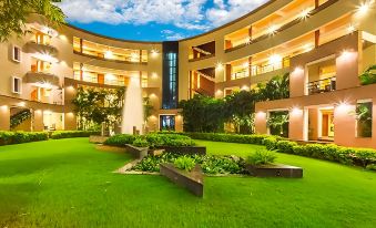 a modern building with a circular entrance and greenery , surrounded by white walls and blue lights at Malligi,Hampi