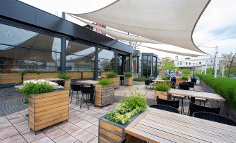 a rooftop terrace with wooden tables , chairs , and potted plants under a large white awning at Hotel Grand