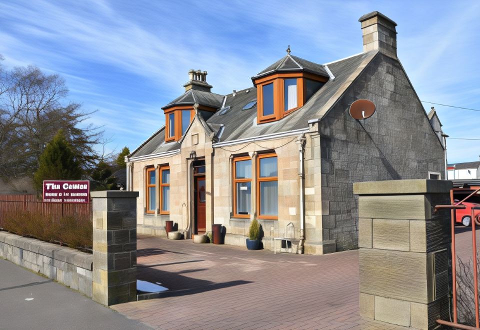 a large stone house with a red roof and orange windows is situated on a street at The Gables