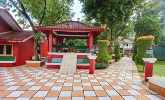 a red and white building with a checkered floor , surrounded by trees and bushes , in a park - like setting at Losmen Kebun Indah