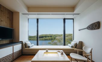 The room features large windows and an attached living area with white couches at Hoshino Resorts KAI Poroto