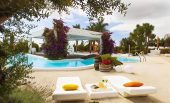 a pool area with white lounge chairs and a large , open - air structure in the background at Augusta Eco Wellness Resort 4 - SPA Access included