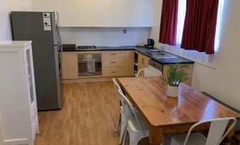 a kitchen with a dining table and chairs , as well as a refrigerator and microwave at Hello Adelaide Motel and Apartments