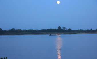 a large body of water with a boat floating on it , illuminated by the moonlight at That Phanom River View Hotel