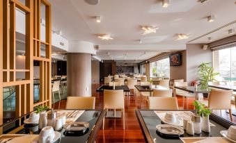a modern restaurant with wooden floors , white walls , and large windows , featuring multiple dining tables and chairs at Nafs Hotel