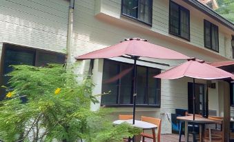 a wooden house with a patio area featuring tables and chairs , an umbrella , and a tree at Flower Garden