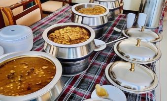 a dining table filled with a variety of food , including bowls of curry , rice , and other dishes at Plaza INN Hotel