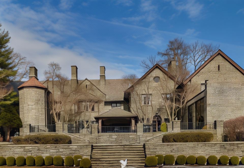 a woman and a child are standing in front of a large stone house with steps leading up to it at Inn at Villanova University