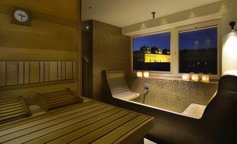 a modern hotel room with a large window , wooden bed , and a view of the city at night at Hotel Maribor & Garden Rooms