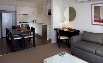 a modern kitchen and living room with a gray couch , white table , black coffee table , and modern appliances at Quest Sanctuary Lakes