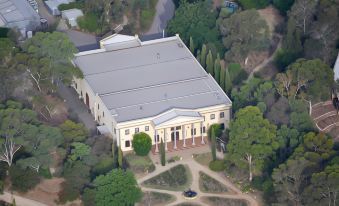 a large white building with a gray roof surrounded by trees and other greenery , located in a park - like setting at Lyndoch Hill