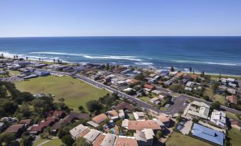 a bird 's eye view of a residential area near the ocean with houses , green spaces , and trees at Lennox Beach Resort