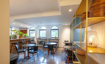 a modern , minimalist café with wooden furniture and large windows , featuring black chairs and wooden tables at Hotel the Shepherd