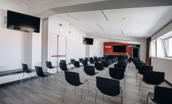 a conference room with rows of black chairs arranged in a semicircle , facing a screen on the wall at Hotel Continental