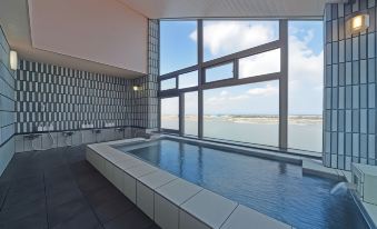 a modern indoor pool with a panoramic view of the ocean through large windows , under a clear blue sky at Yamadaya
