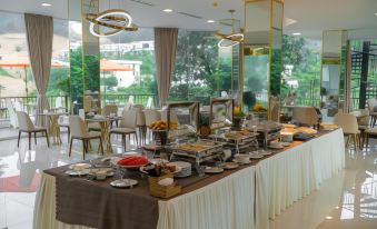 a dining room with a long buffet table filled with a variety of food items , including bowls , cups , and utensils at Ivory Villas & Resort