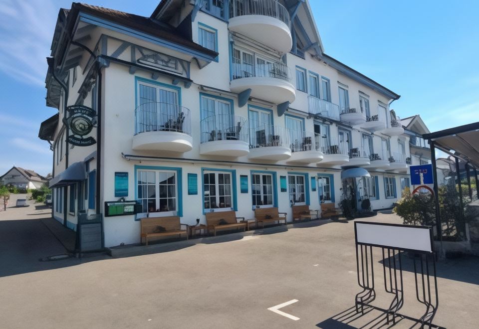 a white building with balconies and a sign in front of it , surrounded by trees and a parking lot at Hotel Amelia