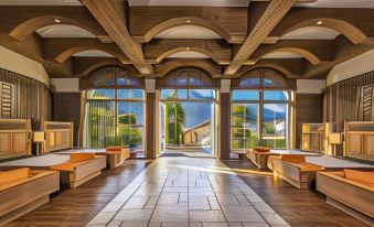 a luxurious hotel lobby with high ceilings , large windows , and wooden floors , providing an inviting atmosphere for guests at Preidlhof Luxury Dolce Vita Resort
