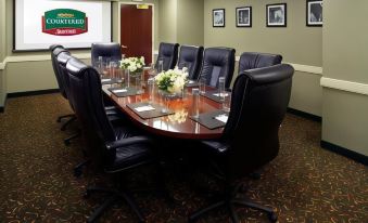 a conference room with a long table , chairs , and flowers is set up for a meeting at Courtyard Columbus New Albany