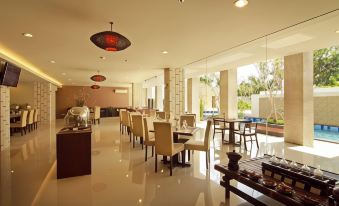 a large , open dining room with tables and chairs arranged for a group of people at Bueno Colombo Hotel Yogyakarta