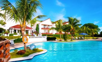 a large swimming pool with a palm tree in the foreground and a building in the background at Thunderbird Resorts - Rizal