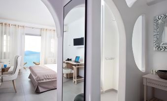 a modern hotel room with a bed , desk , and laptop , reflected in an arched mirror on the wall at Belvedere Suites
