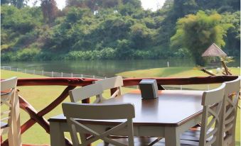 a wooden dining table with chairs and a speaker placed on top of it , overlooking a body of water at Vimannam Resort