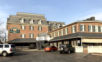 a large hotel building with a parking lot in front of it , where two cars are parked at Waynebrook Inn