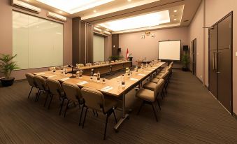 a large conference room with a long table , chairs , and a projector screen set up for a meeting at Pranaya Boutique Hotel