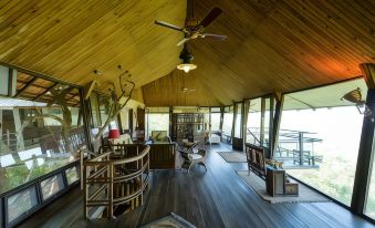 a wooden house with a large deck , featuring a dining table and chairs , as well as a staircase leading to an upper level at The Machan