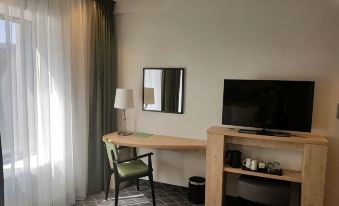 a desk with a lamp and a tv on it in a room with a window at Hampton by Hilton Antwerp Central Station