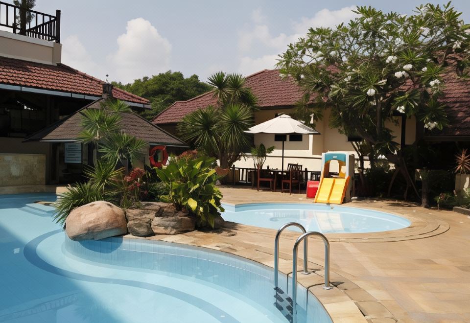 a backyard with a pool , slide , and playhouse is surrounded by trees and houses , and people are sitting on the porch at Resor Tuban Tropis