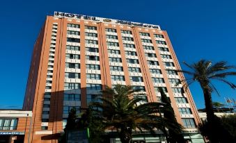 "a tall building with a sign that says "" hotel amman "" is surrounded by palm trees" at Hotel Albufera