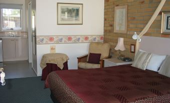 a cozy hotel room with a bed , couch , and chairs , as well as a dining table and chairs at The Balnarring Motel