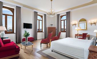 a luxurious hotel room with a large bed , two chairs , and a tv , all arranged in a modern style at Sina Brufani