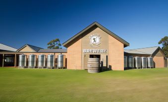 a large building with a brewery sign and barrels in front , under a clear blue sky at Potters Apartments