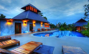 a large swimming pool with lounge chairs and a gazebo in front of it , surrounded by trees at Chalicha Resort