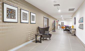 a hallway with beige tiled walls and a large window , featuring three framed pictures on the wall at Quest Liverpool
