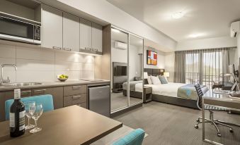 a modern hotel room with a kitchenette , dining table , and bed , all connected to a living area at Quest Liverpool