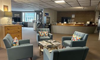 a room with blue chairs and a wooden coffee table in front of a counter at The Lancaster Motel