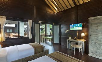a hotel room with two beds , a desk , and a television mounted on the wall at Coconut Boutique Resort