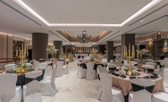 a large banquet hall with white tables , chairs , and black tablecloths , as well as chandeliers hanging from the ceiling at Neelkanth Sarovar Premiere