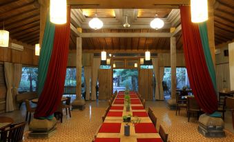 a long dining table with red tablecloths and chairs is set up in a room with wooden walls at Rumah Batu Boutique Hotel