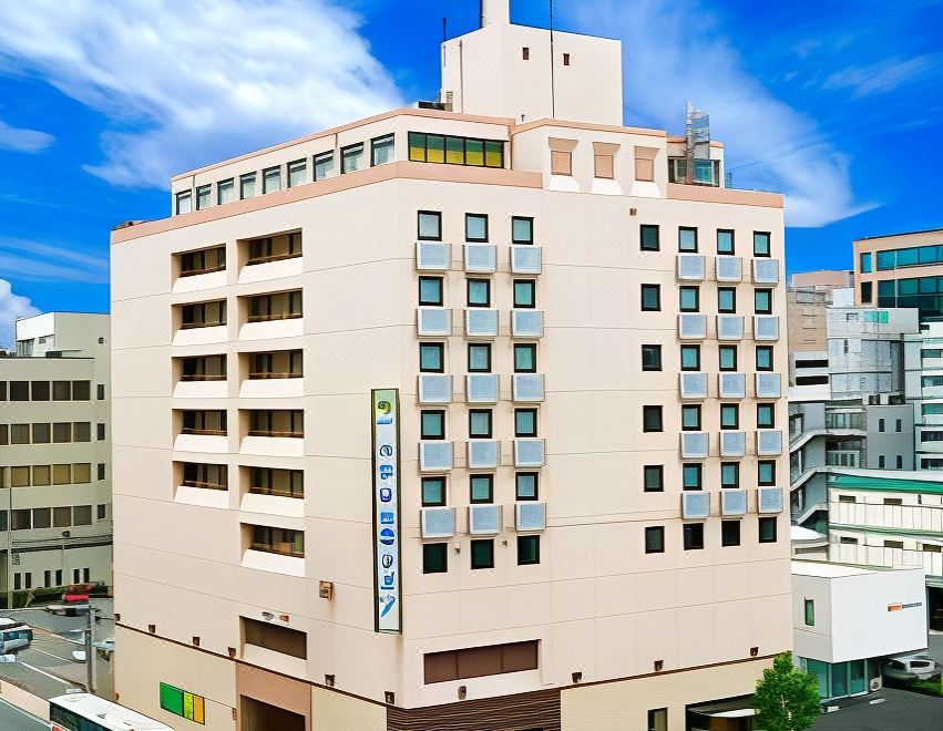 "a large , beige - colored building with multiple floors and a sign for "" hotel m "" is situated in a city street" at Hotel Hokke Club Kumamoto